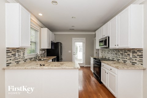 A kitchen with white cabinets and a black refrigerator.
