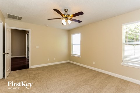 a bedroom with a ceiling fan and a door to a hallway