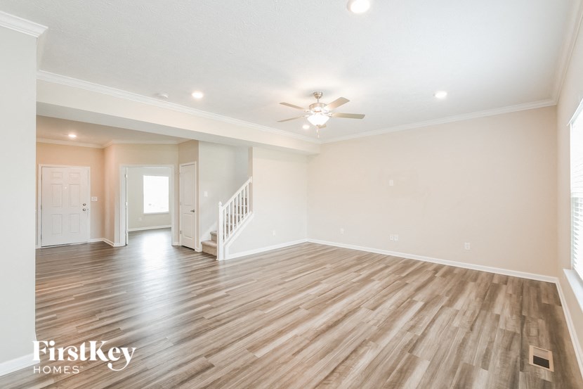 an empty living room with wood flooring and a ceiling fan