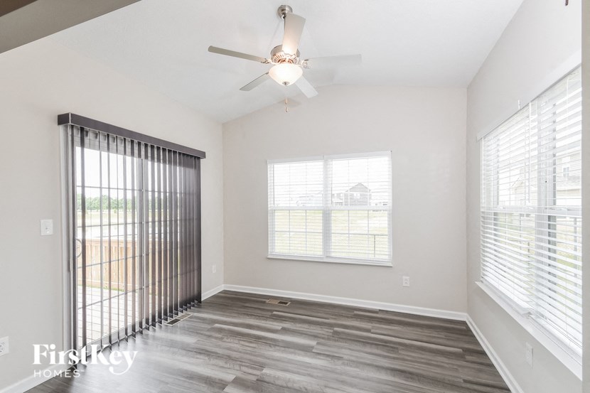 an empty living room with a ceiling fan and a window