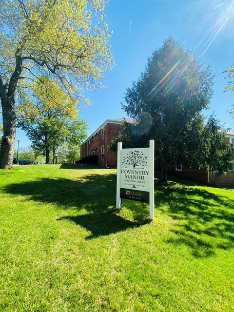 a sign in the grass in front of a building