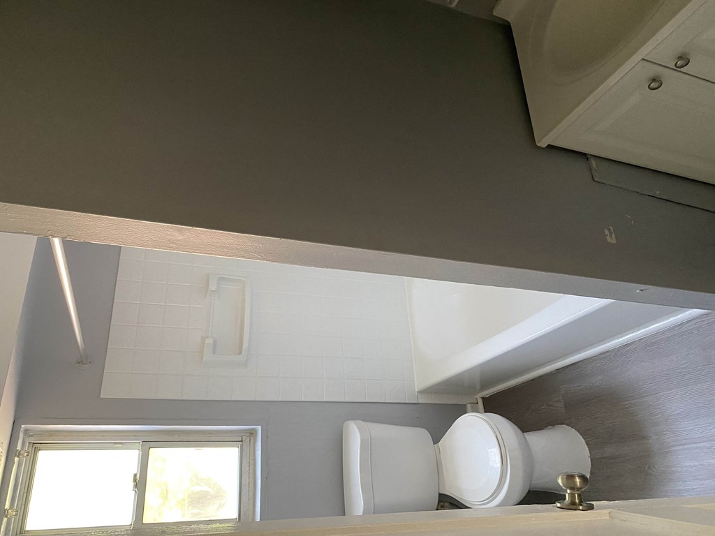 a bathroom with a toilet and a mirror above it