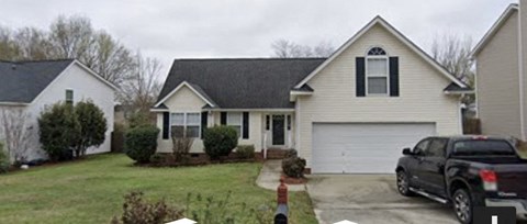 A white house with a black roof and a garage door.