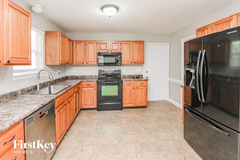 A kitchen with orange cabinets and a black refrigerator.