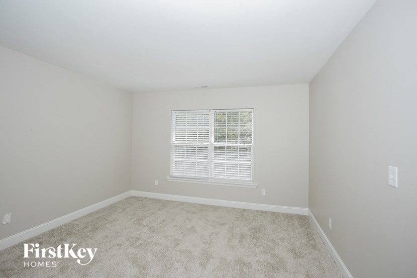 a bedroom with white carpet and a window