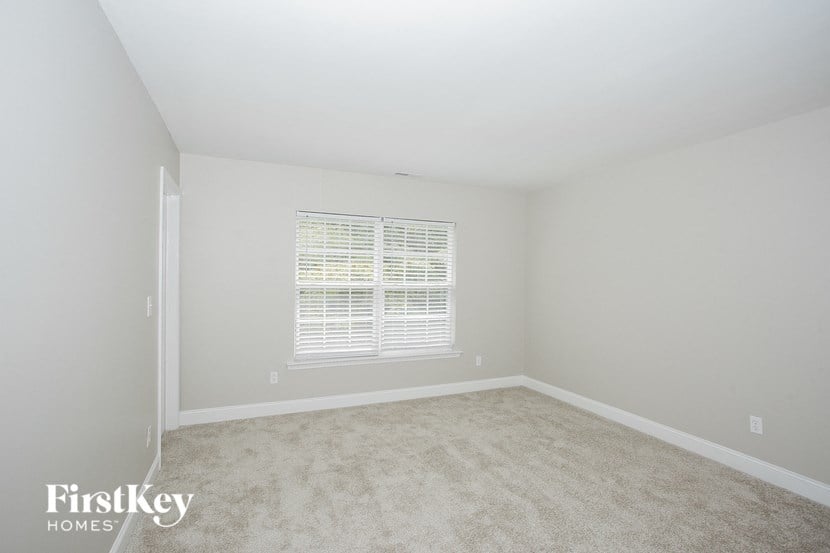 a bedroom with white carpet and a window