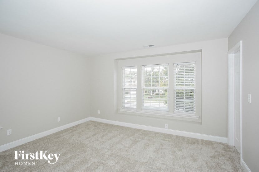 a bedroom with a large window and a carpeted floor