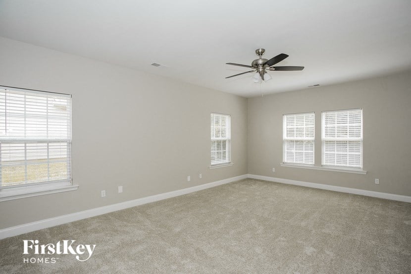 a living room with a ceiling fan and two windows