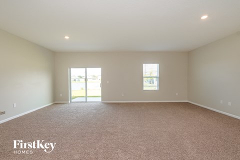 A spacious room with a carpeted floor and two windows.
