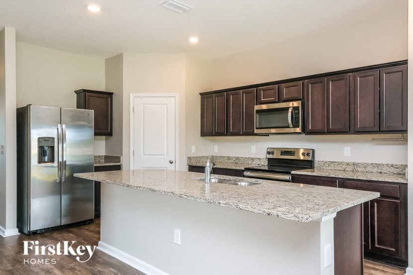 A kitchen with a granite countertop and a stainless steel refrigerator.