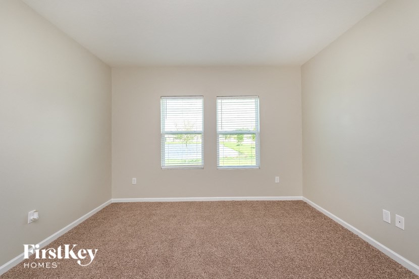 A room with a carpeted floor and a window with blinds.
