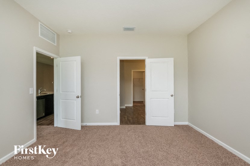A carpeted room with two doors and a small window.