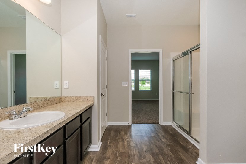 A bathroom with a sink, mirror, and wooden floor.