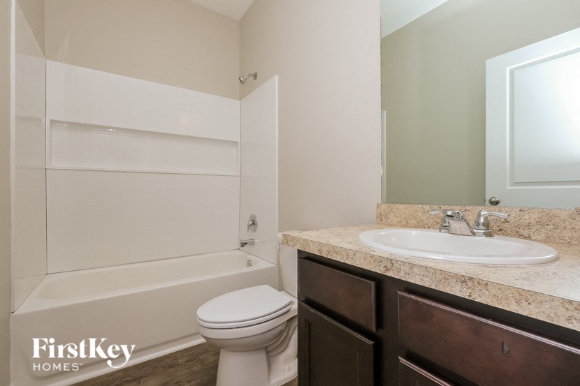 A white toilet sits in a bathroom with a sink and a mirror.