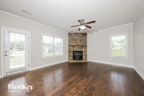 an empty living room with a fireplace and a ceiling fan
