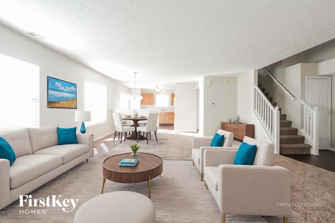 A living room with a white couch and a painting of a beach on the wall.