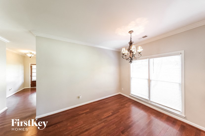 an empty living room with a large window and a chandelier