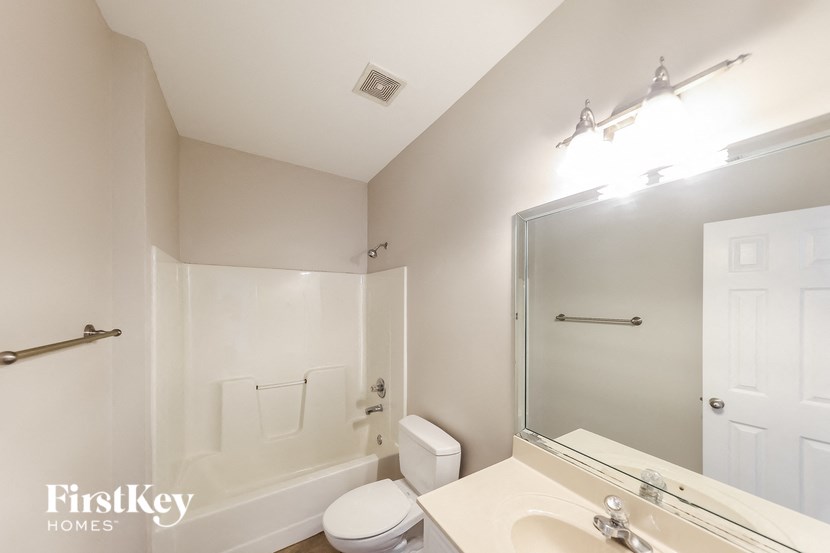 a white bathroom with a large mirror and a white toilet