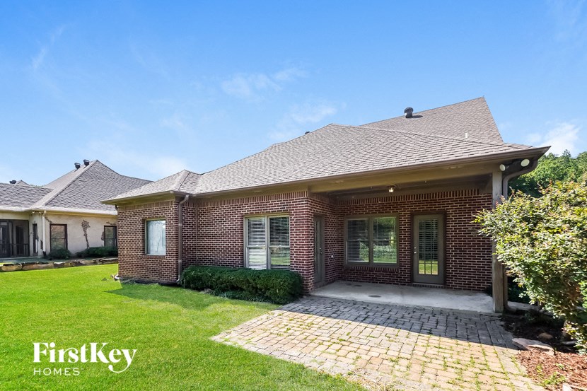 the front of a brick house with a driveway and grass