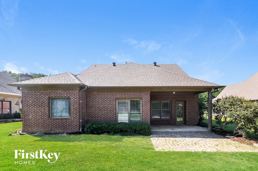 a small brick house with a covered porch and a lawn