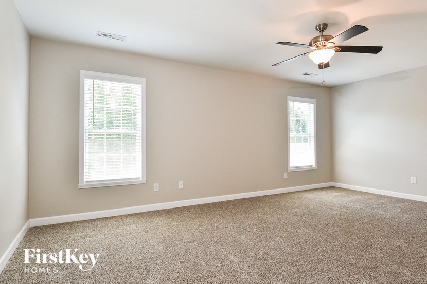 an empty room with a ceiling fan and two windows