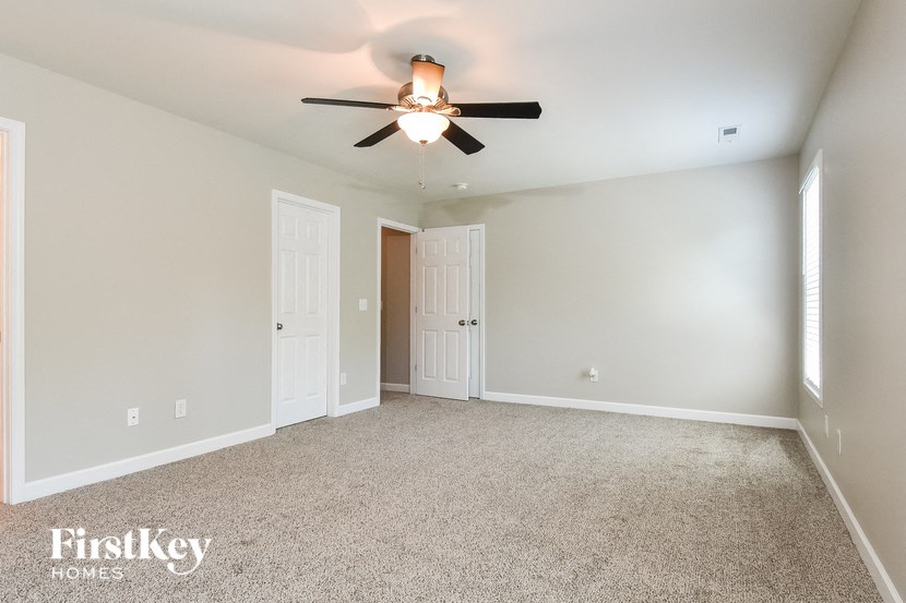 a empty living room with a ceiling fan and a door