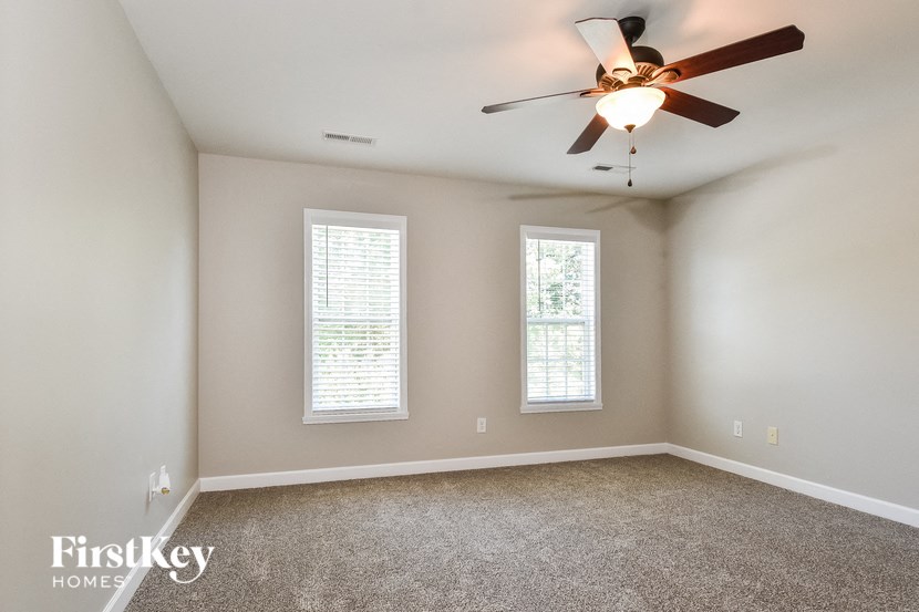 an empty room with a ceiling fan and two windows