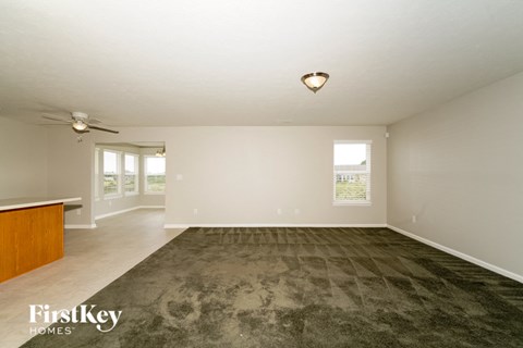 a living room with a carpet and a ceiling fan