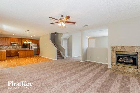 A spacious living room with a fireplace and a staircase.