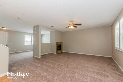 A spacious room with a fireplace and a ceiling fan.