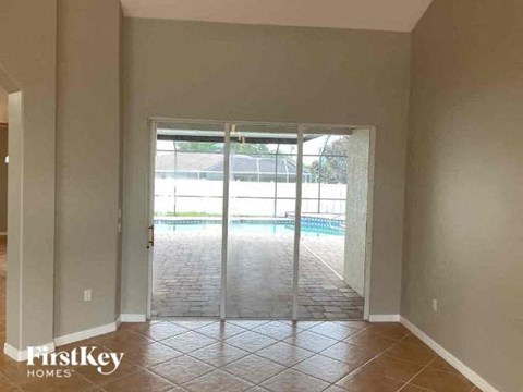 an empty living room with sliding glass doors to a pool