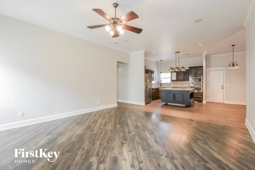 A spacious room with a fan and wooden flooring.