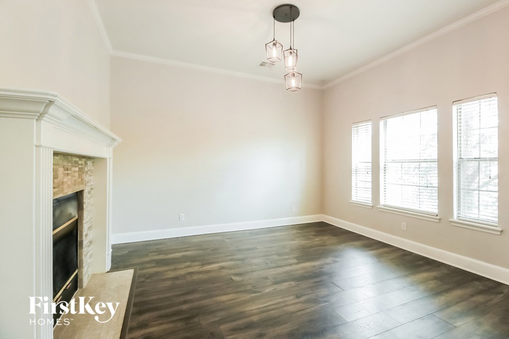 A large empty room with a fireplace and wooden floors.