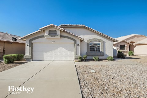 a white house with a white garage door and a gravel driveway