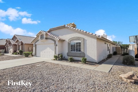 a white house with a white garage door and a gravel driveway