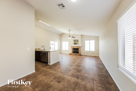 an empty living room with a kitchen and a fireplace