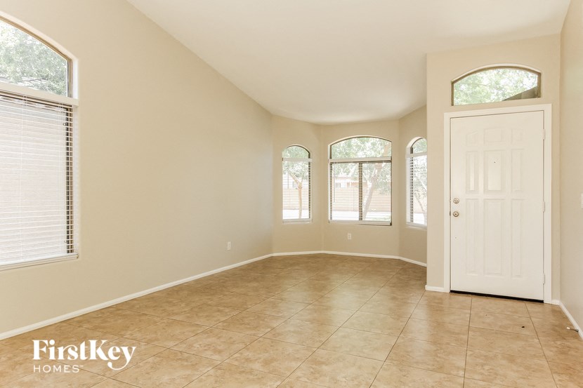 an empty living room with a white door and three windows
