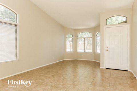 an empty living room with a white door and three windows