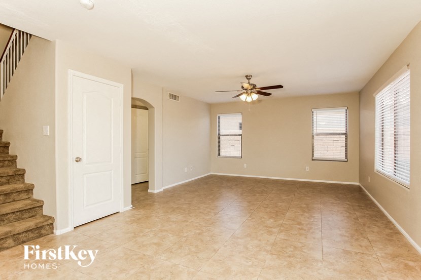 an empty living room with a ceiling fan and a staircase