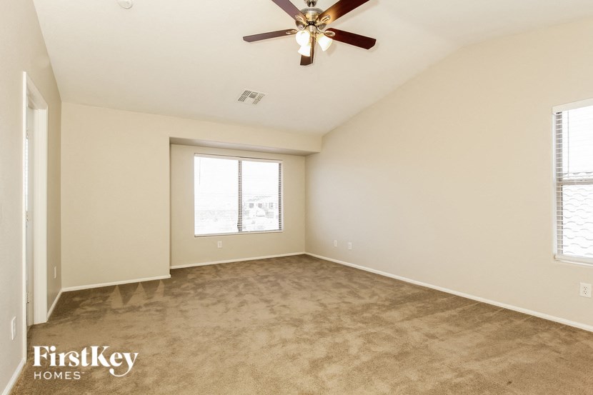 an empty living room with a ceiling fan and a window
