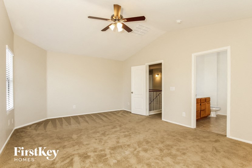 an empty living room with a ceiling fan and a door to a bathroom
