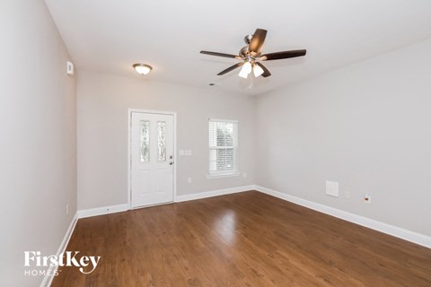 a living room with white walls and a ceiling fan