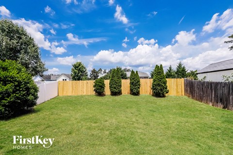 the backyard of a house with a wooden fence and grass and trees