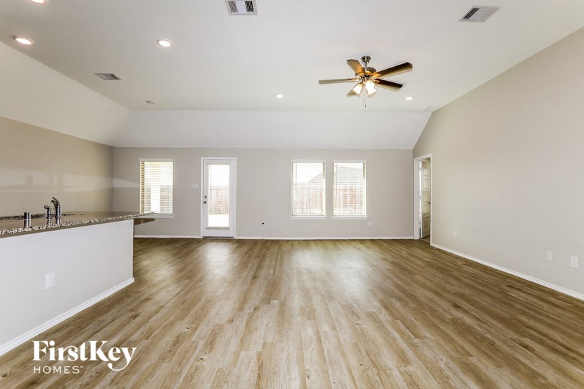 A spacious room with wooden floors and a ceiling fan.