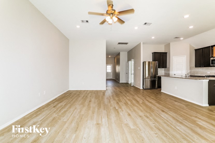 A spacious room with wooden floors and a ceiling fan.