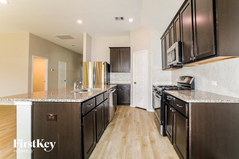 A modern kitchen with dark wood cabinets and a granite countertop.