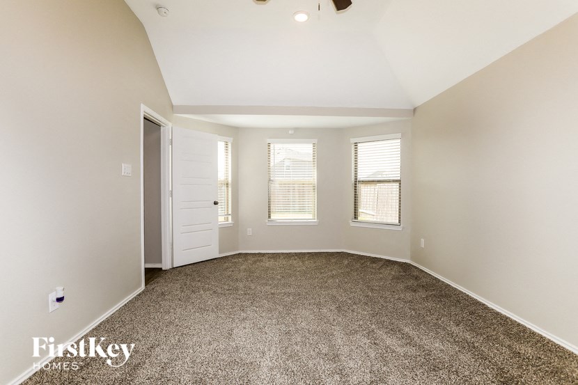 A spacious room with a carpeted floor and a ceiling fan.