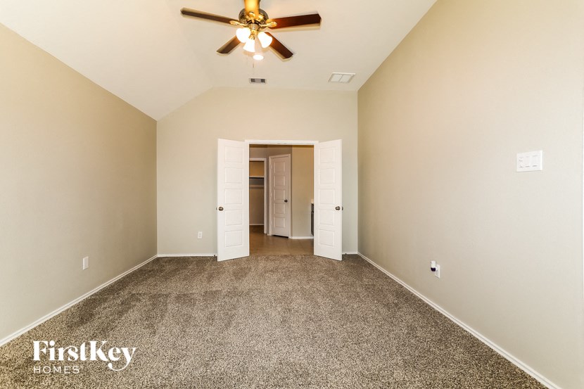 A spacious room with a ceiling fan and carpeted floor.