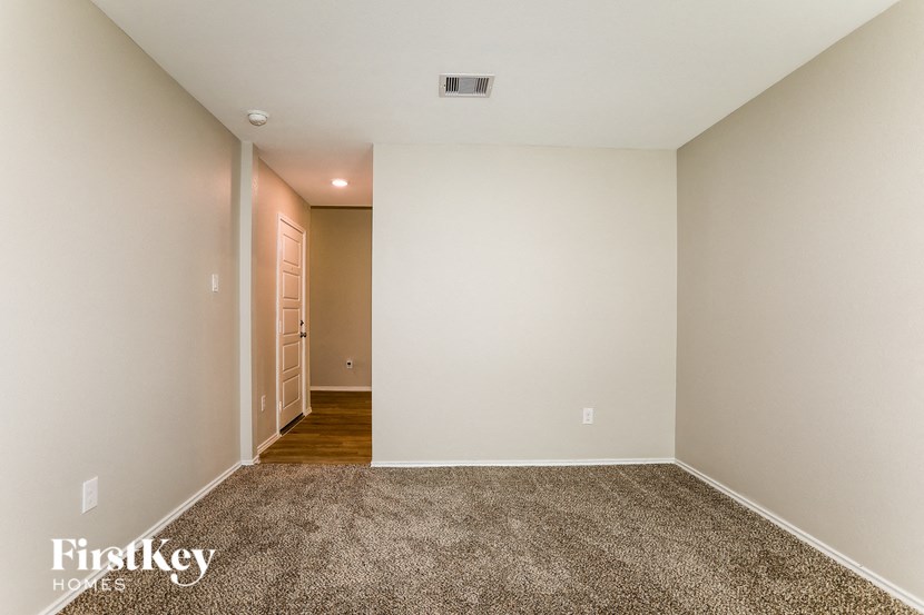A carpeted room with a doorway leading to another room.