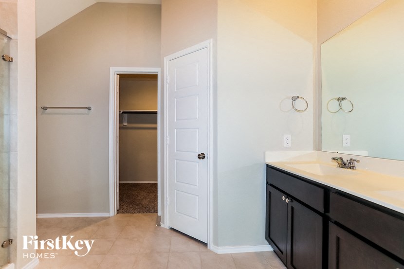 A bathroom with a white door and a mirror.